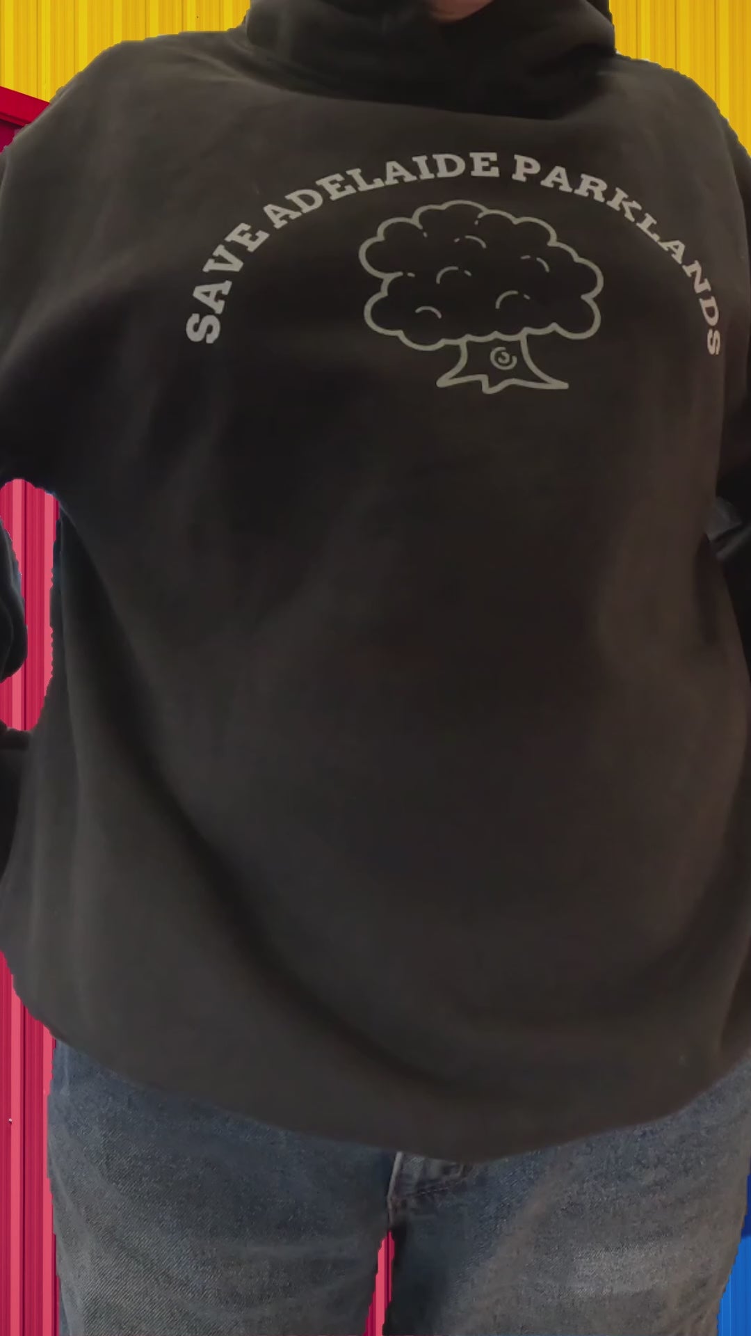Grey Save Adelaide Parklands hoodie shown being worn from different angles in a colourful outdoor setting